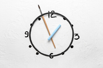 Creative clock made of brush and chalk on white background