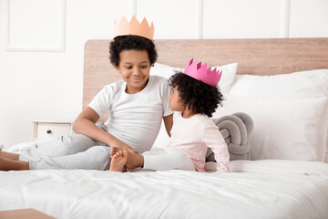 African-American children sitting on bed in room