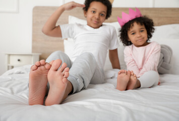 African-American children sitting on bed in room