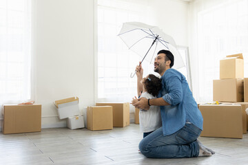 Happy moment family. Father and daughter relax in living room holding the white umbrella. Just moving new house many parcel box on the floor.