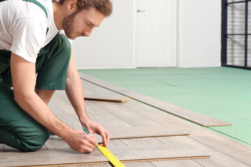 Carpenter taking measurements of laminate flooring in room