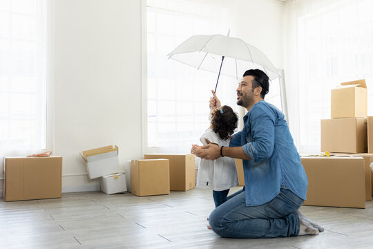 Happy moment family. Father and daughter relax in living room holding the white umbrella. Just moving new house many parcel box on the floor.
