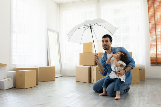 Happy moment family. Father and daughter relax in living room holding the white umbrella. Just moving new house many parcel box on the floor.