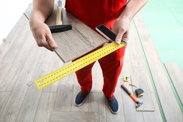 Carpenter taking measurements of laminate flooring in room
