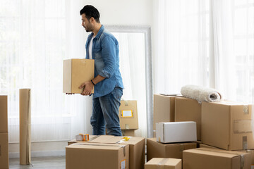 Young man just moving new house. He unpacking parcel box and arranging on the floor in the living room.