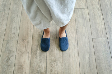 Man in slippers standing on new laminate flooring at home