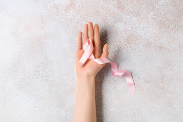 Female hand with pink ribbon on light background. Breast cancer concept