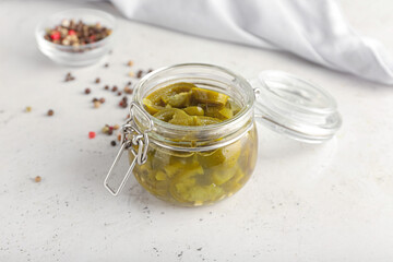 Glass jar with canned jalapeno on light background