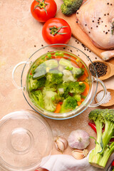 Stylish cooking pot with tasty soup and ingredients on light background