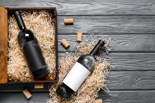 Box with bottles of wine on wooden background