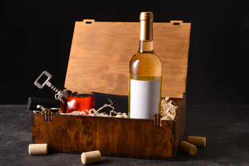 Naklejka premium Box with bottles of wine, glass and corkscrew on dark background