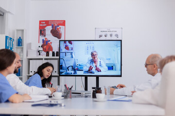 Teamwork discussing sickness treatment during online videocall telemedicine teleconference working in meeting room. Practitioner doctors explaining illness consultation analyzing medical expertise