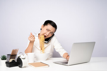 Asian woman working hard overtime eating instant noodles at office.