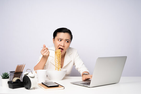 Asian woman working hard overtime eating instant noodles at office.
