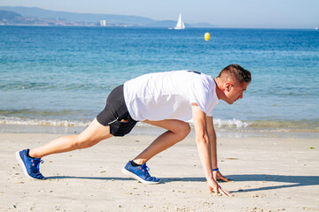 young man in starting position for jogging on the beach