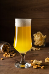 light beer unfiltered with a large strong white foam on a wooden background, copyspace. With beer snacks