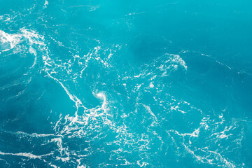 Turquoise ocean water background. Surface of the sea. Natural texture of blue foaming sea water.