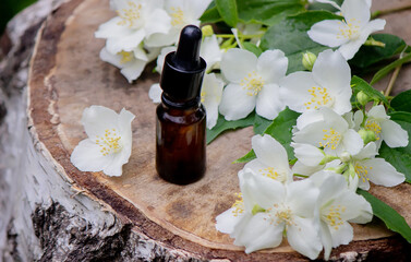 Essential oil and jasmine flowers on a wooden background. Cosmetic procedures.