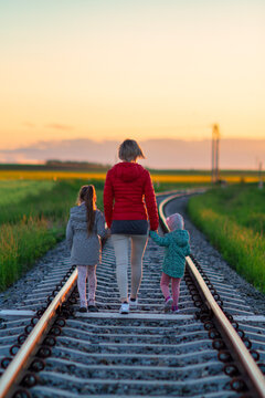 A mother with two daughters is walking along the railway tracks