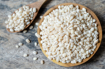 Top view of dry organic wheat seed pile in wooden bowl and spoon on grunge wooden background