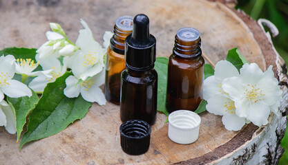Essential oil and jasmine flowers on a wooden background. Cosmetic procedures.