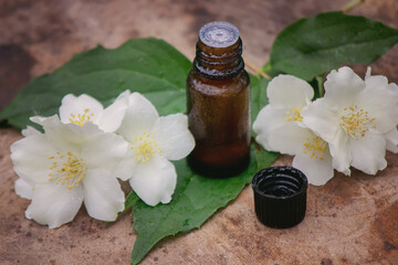 Essential oil and jasmine flowers on a wooden background. Cosmetic procedures.