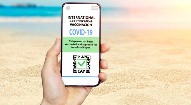 Coronavirus vaccination certificate or vaccine passport for travellers concept. COVID-19 immunity e-passport in the smartphone mobile app for international travelling. Summer travel beach background