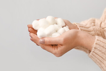 Female hands with soft cotton wool on light background, closeup