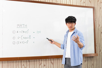 Educational concept a young smart male explaining decision of hard math in a classroom before...