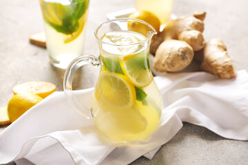 Jug of cold ginger lemonade on grunge background