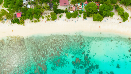 Fototapeta na wymiar Aerial drone of sandy beach and azure water surrounded by a coral reef and an atoll. Alorro Beach, Philippines, Samal.