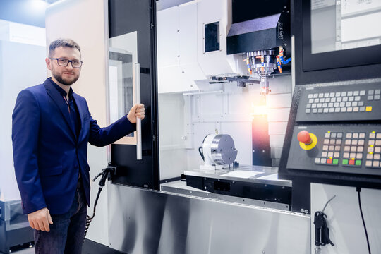 Modern process metal detail production going for car. Worker man entering data in CNC drill machine at automatic factory floor - Powered by Adobe
