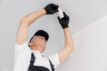 Electrician man worker install lamp lighting and spot loft style on ceiling in apartment or office