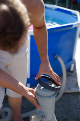 A man checks a filter for cleaning a home pool. Keeping the swimming pool clean