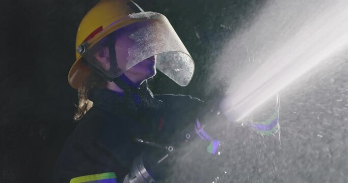 a night shift of a woman firefighter extinguishing a flame