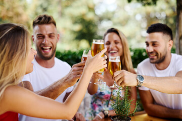 Group of happy friends toasting with beer at the summer bar