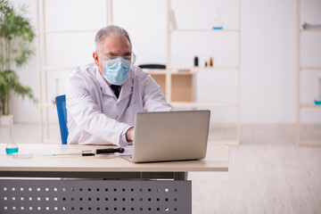 Obraz premium Old male chemist working in the lab during pandemic
