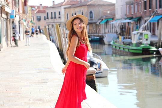 Fashion. Smiling young stylish woman looking back walking in the old town of Murano in Venice, Italy.