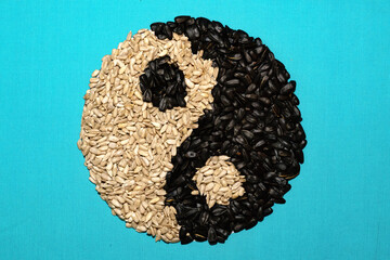 Sunflower seeds in a peel and peeled seeds in the form of yin-yang.