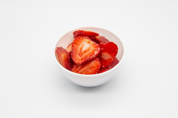 Sliced ​​strawberries in a white plate against white background.