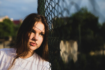 Beautiful cute teenage girl in a white T-shirt walks in the fresh air. The girl looks at the sunset...