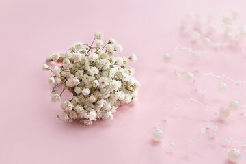 Beautiful gypsophila boutonniere and beads on color background