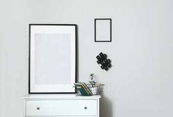 Interior of modern stylish room with chest of drawers and blank photo frames