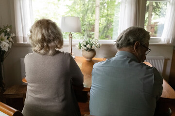 Back view of unhappy mature man and woman spouses sit separately back to back ignore avoid talking...
