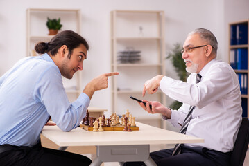 Two businessmen playing chess in the office