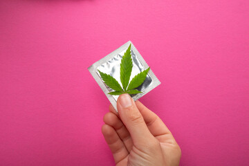 protection in sex when using drugs,condom and cannabis leaf on pink background