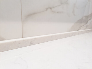Countertop marble skirting board, wall border. White marble countertop, kitchen countertop with white tiles in background. Joint between worktop and wall.