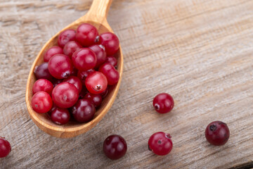 Ripe cranberries in a wooden spoon.