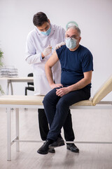 Old male patient visiting young male doctor in vaccination conce