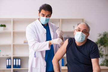 Old man visiting young doctor in covid-19 vaccination concept